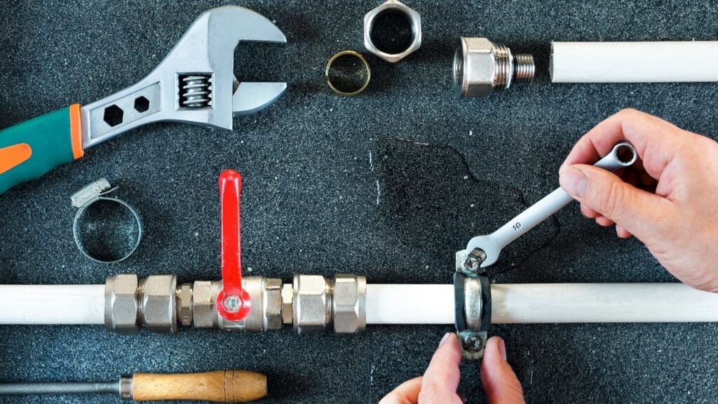 Plumber repairing a pipe valve with an adjustable wrench in Cape Coral