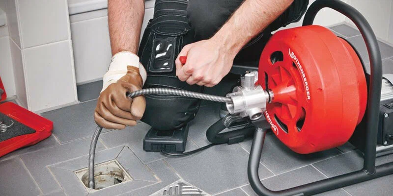 Plumber using a drain-cleaning machine in Cape Coral