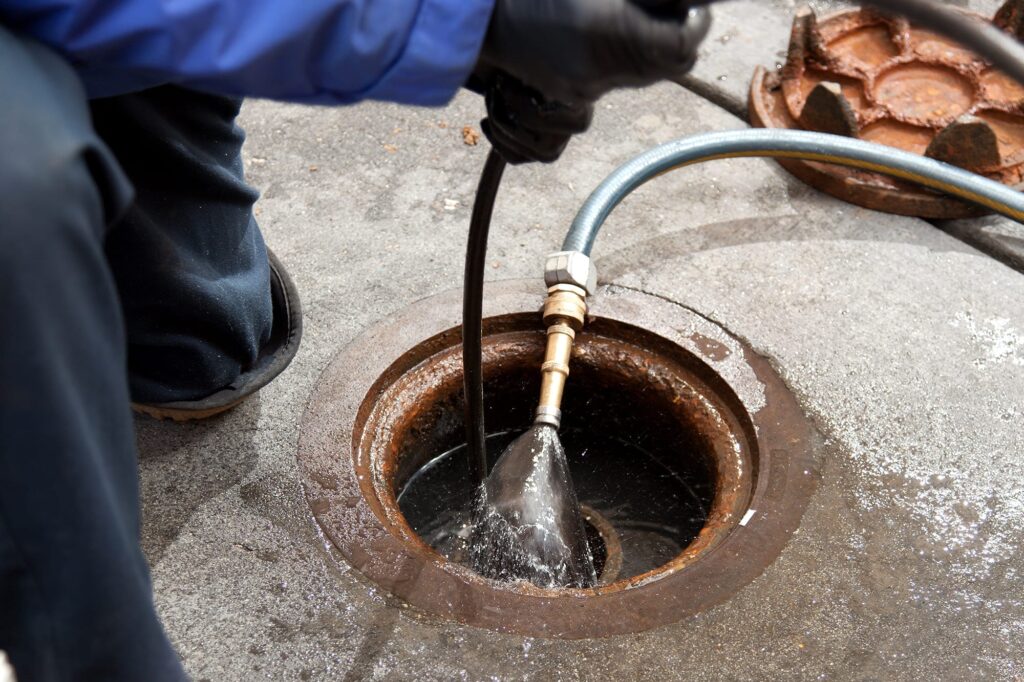 Plumber hydro jetting a sewer line through a manhole in Cape Coral