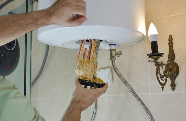 Technician removing mineral buildup from a water heater in Cape Coral